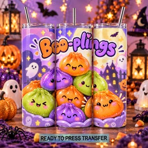 May include: A cylindrical tumbler with a metal straw featuring a colorful Halloween-themed graphic. The design displays cartoon-style dumplings with smiling faces in orange, green, and purple, set against a background of ghosts and text reading Boo-plings.