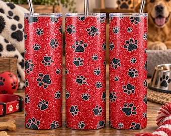 May include: Three cylindrical tumblers with a vibrant red glitter finish and a repeating pattern of black paw prints. Each tumbler features a clear lid and a straight silver metal straw inserted at the top. The design is consistent across all three.