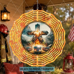 May include: A circular metal wind spinner featuring a wavy orange and yellow border. The center displays a graphic of a cross formed by firefighters in gear, with fire trucks below against a mountain backdrop. It hangs from a silver chain.