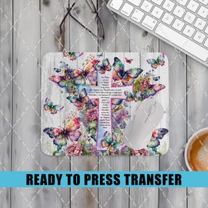 May include: A sublimation design featuring a white wooden background with a cross and butterflies in shades of pink, purple, and blue. The cross has the Lord's Prayer printed on it. This design is ready to be pressed onto a variety of items.