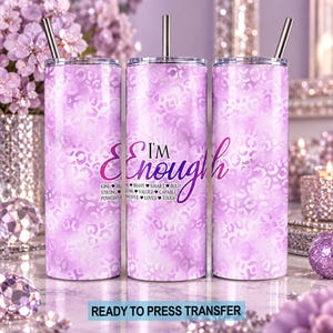 May include: Three cylindrical tumblers with a light purple leopard print pattern. The center tumbler features the text I'M ENOUGH in a purple script font, accompanied by a list of words including KIND, BRAVE, SMART, BOLD, STRONG, VALUED, CAPABLE, POWERFUL, LOVED, and TOUGH.