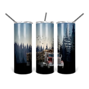 May include: A stainless steel tumbler with a red and black logging truck hauling logs through a forest. The truck is driving through a forest with a blue sky and birds flying overhead. The tumbler has a black lid and a straw.