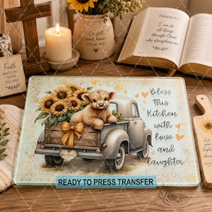 May include: A rectangular glass cutting board featuring a light-colored vintage pickup truck carrying a fluffy Highland cow and a bouquet of sunflowers. The text reads, Bless This Kitchen with love and laughter. The background has gold speckles.