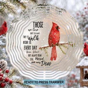 May include: A circular metal wind spinner featuring a red cardinal perched on a branch. The text reads: THOSE we love DON'T GO AWAY THEY WALK BESIDE US EVERY DAY Unseen, Unheard BUT ALWAYS NEAR STILL MISSED still very Dear. The design includes white snow.