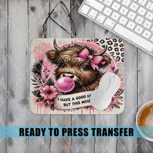 May include: A rectangular mousepad featuring a brown Highland cow with a pink bow and bubblegum. The design includes pink flowers and the text "I HAVE A GOOD HEART BUT THIS MOUTH". A white mouse and keyboard are also visible.