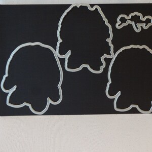 May include: Four metal die-cut shapes on a black background. The shapes are of a person, a flower, and two different sized circles.