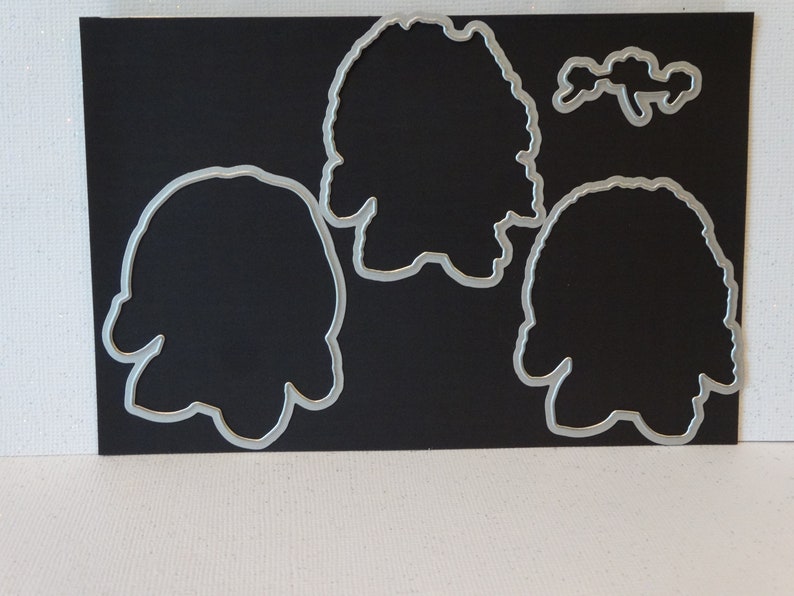 May include: Four metal die-cut shapes on a black background. The shapes are of a person, a flower, and two different sized circles.
