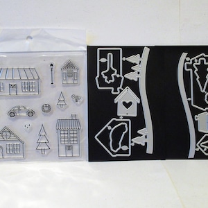 Puede incluir: Un conjunto de sellos transparentes y troqueles de metal con un tema de pueblo de invierno. Los sellos incluyen casas, árboles, un coche, una corona, una farola y un buzón. Los troqueles incluyen casas, árboles, un coche, una corona, una farola y un buzón.