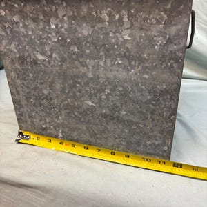 Peut inclure: Un seau rectangulaire en m&eacute;tal galvanis&eacute; avec une poign&eacute;e. Le seau mesure environ 30 cm de haut et a une surface textur&eacute;e. Un ruban &agrave; mesurer jaune est plac&eacute; &agrave; c&ocirc;t&eacute; du seau.