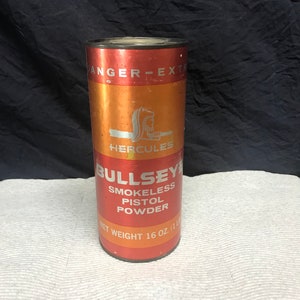 May include: A red and orange metal container with the text "ANGER-EXTR" and "HERCULES" printed on it. The container also has the text "BULLSEYE SMOKELESS PISTOL POWDER" and "NET WEIGHT 16 OZ. (1 LB)" printed on it.
