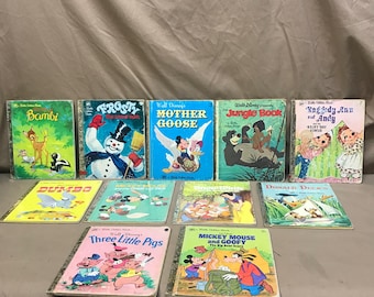 Könnte beinhalten: Eine Sammlung von Vintage-Kinderbüchern mit klassischen Disney-Figuren und -Geschichten. Zu den Titeln gehören "Bambi", "Frosty", "Mother Goose", "Das Dschungelbuch" und "Raggedy Ann and Andy". Die Bücher haben farbenfrohe Einbände und goldfarbene Buchrücken.