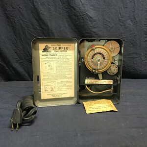 May include: A vintage Skipper brand time switch with a black cord and plug. The switch is labeled "MODEL TS66SP-S" and has a clock motor rating of 1/2 HP. The switch has a caution label that reads "DO NOT CONNECT TO ANY LOAD IN EXCESS OF 12 VAC. 15 AMP."