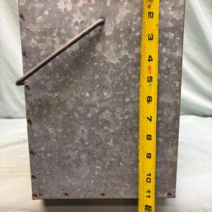 Peut inclure: Un seau en m&eacute;tal galvanis&eacute; avec une poign&eacute;e. Le seau rectangulaire mesure environ 33 cm de haut. Le m&eacute;tal a un aspect mouchet&eacute; et le seau a un design simple et utilitaire.