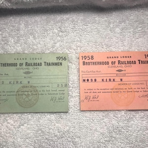 May include: Two vintage membership cards from the Brotherhood of Railroad Trainmen. One is green and dated 1956, the other is orange and dated 1958. Both cards feature the name Moss Kirk W.