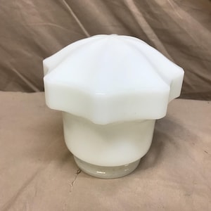 May include: A white glass lamp shade with a starburst design on top. The shade has a rounded base and a textured, opaque surface. The lamp shade is likely for a vintage or retro-style lamp.