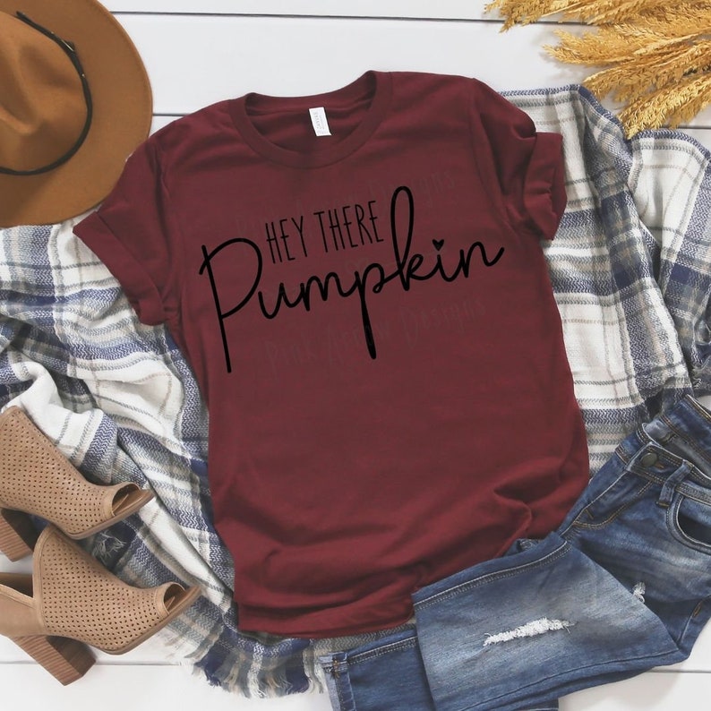 May include: A maroon t-shirt with the text "Hey there Pumpkin" in black lettering with a small heart symbol.