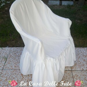 May include: White chair cover with a ruffled bottom. The cover is made of a soft, white fabric and has a simple, elegant design.