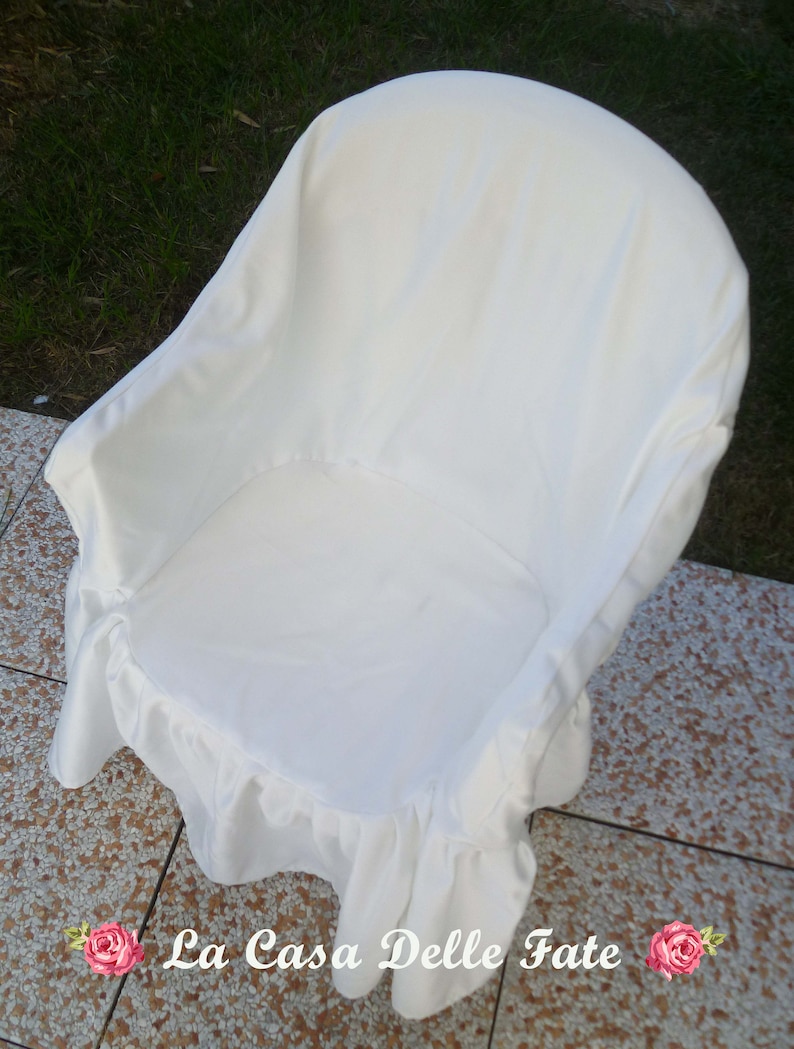 May include: White chair cover with a ruffled edge. The cover is made of a soft, white fabric and is designed to fit over a standard chair.