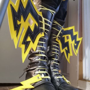 May include: Black leather boots with yellow lightning bolt accents. The boots have yellow laces and are decorated with yellow lightning bolt shapes.