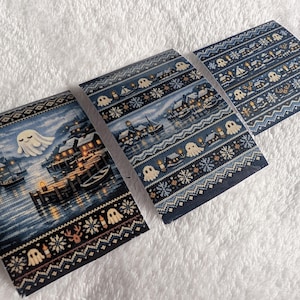 May include: Three rectangular stickers featuring a dark blue winter harbour scene with a ghost, snow-covered houses, and boats. The design includes a repeating fair isle pattern border with small ghosts, snowflakes, and reindeer motifs.