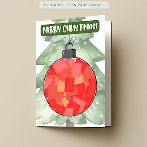 May include: A folded greeting card featuring a DIY torn paper craft design. The card displays a watercolor-style green Christmas tree with a large red ornament made of layered paper scraps. The text MERRY CHRISTMAS! appears in white on a green banner.