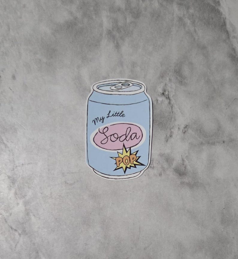 May include: A light blue sticker in the shape of a soda can with the words "my Little Soda" in cursive and a pink oval. A yellow "POP" burst graphic is at the bottom.