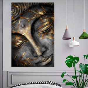 Puede incluir: Un primer plano de un rostro de Buda de piedra gris con detalles en pan de oro. Los ojos del Buda están cerrados y el rostro tiene una expresión serena. El fondo es gris oscuro.