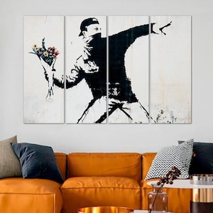 Op de afbeelding: Een zwart-witte multi-panel canvas print van een gemaskerd figuur dat een boeket bloemen gooit. De figuur draagt een zwarte hoodie en een zwarte broek. De achtergrond is wit met een korrelige textuur.