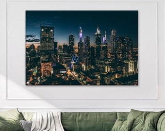 May include: An aerial view of a city skyline at night. The buildings are illuminated with lights, creating a vibrant and colorful scene. The city is surrounded by a dark sky, with a few stars visible.