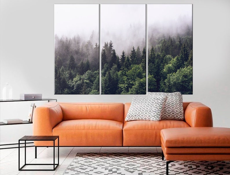 May include: A three-panel canvas print featuring a misty forest scene. The image shows a dense forest with tall trees and a layer of fog covering the ground. The colors are muted and the overall effect is calming and serene.