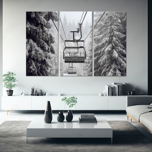 May include: A three-panel canvas print showing a winter scene. The central panel features a ski lift, with snow-covered fir trees on either side. The artwork is in monochrome, creating a tranquil winter landscape.