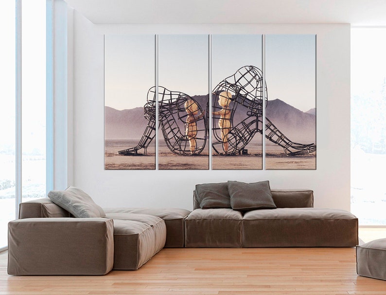 Puede incluir: Una impresi&oacute;n en lienzo de varios paneles que presenta una obra de arte contempor&aacute;nea de dos figuras en un paisaje des&eacute;rtico. Las figuras est&aacute;n hechas de malla de alambre y est&aacute;n posadas de una manera que sugiere que se abrazan o se protegen mutuamente.