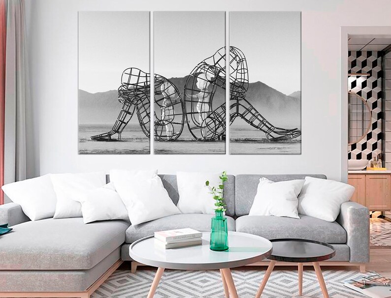May include: A black and white photograph of a metal sculpture of two figures intertwined. The sculpture is in a desert landscape.