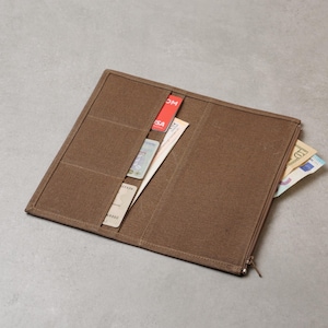 Può includere: Un portafoglio lungo in tela marrone con molteplici fessure per carte e uno scomparto laterale. Il portafoglio è aperto, rivelando diverse carte di credito e banconote inserite nelle tasche, mostrando un design funzionale.