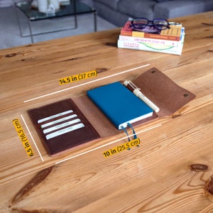 May include: A brown leather notebook cover with a blue notebook, pen, and credit card slots. The cover measures 14.5 inches by 6.5 inches.