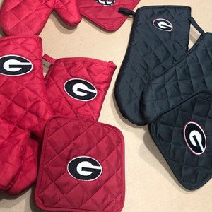 May include: Set of red and black oven mitts and pot holders with a white "G" logo.