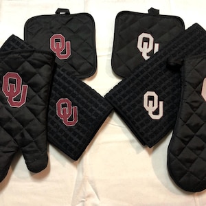 May include: Set of black quilted oven mitts and pot holders with the embroidered Oklahoma Sooners logo in maroon.