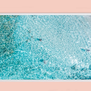 May include: An aerial view of a turquoise blue ocean with sparkling sunlight reflecting off the water.