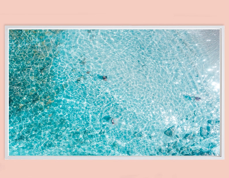 May include: An aerial view of a turquoise blue ocean with sparkling sunlight reflecting off the water.