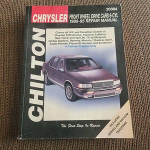 May include: A Chilton repair manual for Chrysler front wheel drive cars, 6-cylinder models from 1988-95. The cover features a maroon car and includes wiring and vacuum diagrams. The manual covers various Chrysler models.