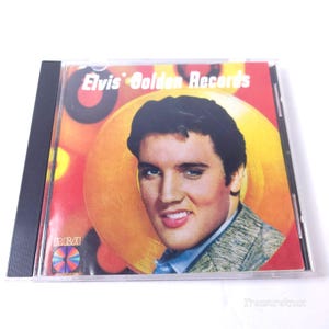 May include: A compact disc case featuring the album cover for Elvis' Golden Records. The cover displays a portrait of Elvis Presley against a yellow and red background with circular graphic elements. The RCA logo is visible in the bottom left corner.