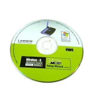 May include: A Linksys Wireless-G USB Network Adapter CD-ROM. The disc has a green and white design with the Linksys logo, a graphic of a wireless router, and the text "Wireless-G USB Network Adapter" and "Setup Wizard".