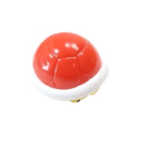 May include: A red turtle shell with a white trim, a recognizable item from a popular video game. The shell is a vibrant red color and has a glossy finish. The white trim adds a contrasting border to the shell.