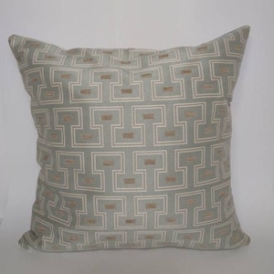 May include: A light blue throw pillow with a geometric pattern in a light brown color.