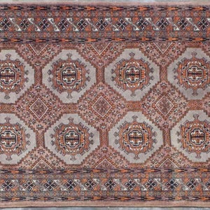 Puede incluir: Una alfombra tradicional con un patrón repetido de octógonos y diamantes en tonos de rojo, blanco y azul. La alfombra tiene un borde con flecos.