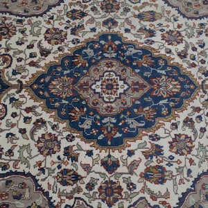 Puede incluir: Una alfombra de color crema con un dise&ntilde;o detallado e intrincado en tonos de azul, marr&oacute;n y rojo. La alfombra presenta un medall&oacute;n central con forma de diamante y motivos florales.