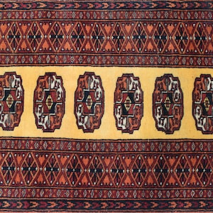 Puede incluir: Una alfombra larga y estrecha con un diseño persa tradicional. La alfombra tiene un fondo amarillo con un patrón repetitivo de formas geométricas rojas, negras y blancas. La alfombra está bordeada por un patrón geométrico rojo y negro.