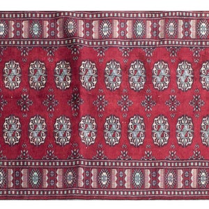 Puede incluir: Una alfombra de pasillo roja con un diseño persa tradicional que presenta intrincados patrones florales y geométricos. La alfombra tiene flecos blancos en ambos extremos.