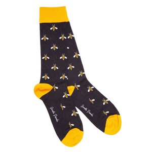 May include: A pair of black socks with a yellow bee pattern. The socks have a yellow cuff and the words "Sweet Pands" are written on the bottom of the socks.