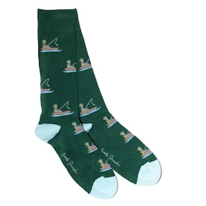 May include: Green socks with light blue heels and toes, patterned with a person fishing from a boat. The words "Smile Provider" are printed on the side of each sock. A fun accessory for any outfit.